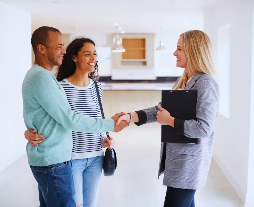 A couple shaking a realtor's hand in the kitchen of a home