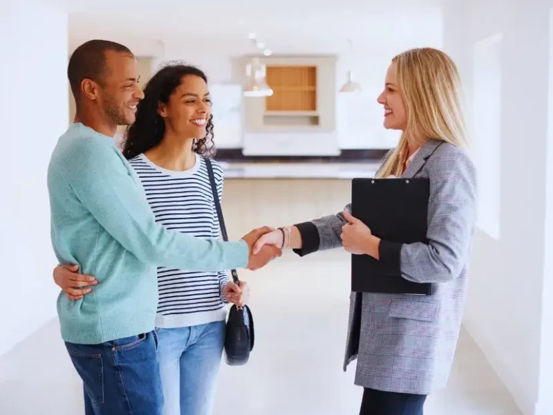 A couple shaking a realtor's hand in the kitchen of a home