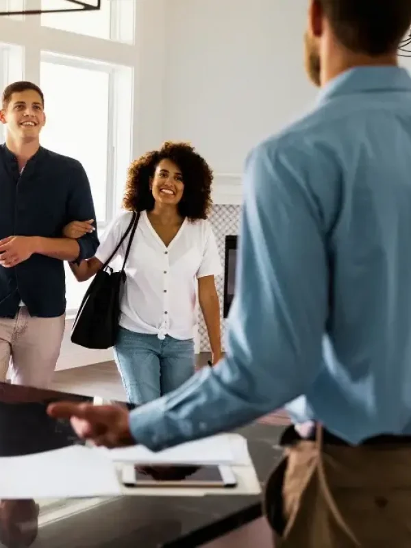 A couple looking around a new home with smiles on their faces as they approach a realtor