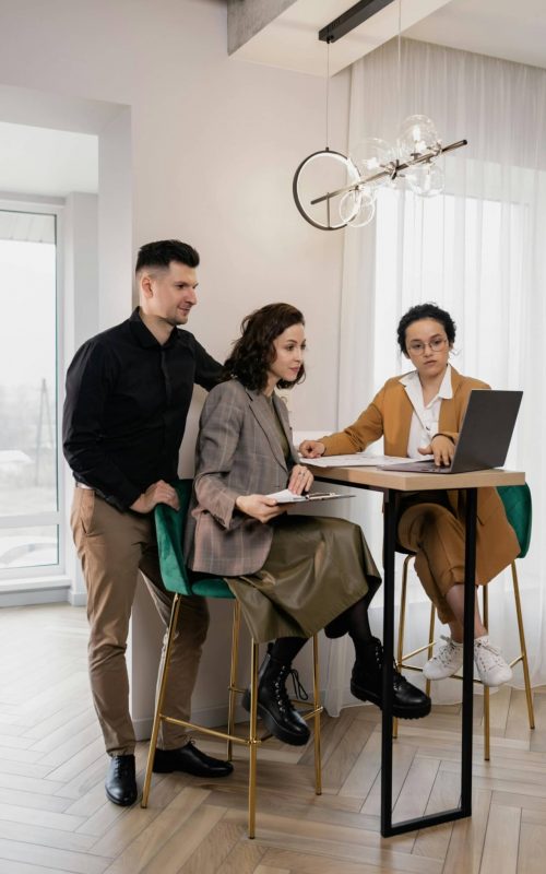 Couple sits at a bar height table and looks at the realtor's laptop